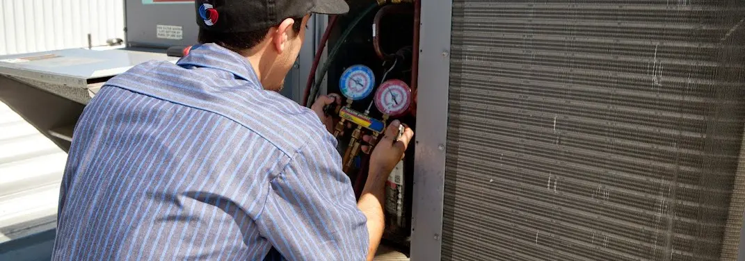 HVAC technician servicing a condenser unit in Sansom Park
